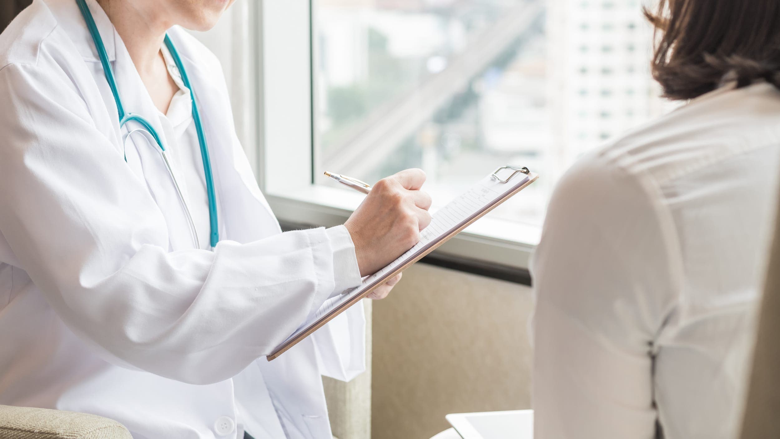 Doctor holding a clipboard educating a patient about STI testing before trying to conceive