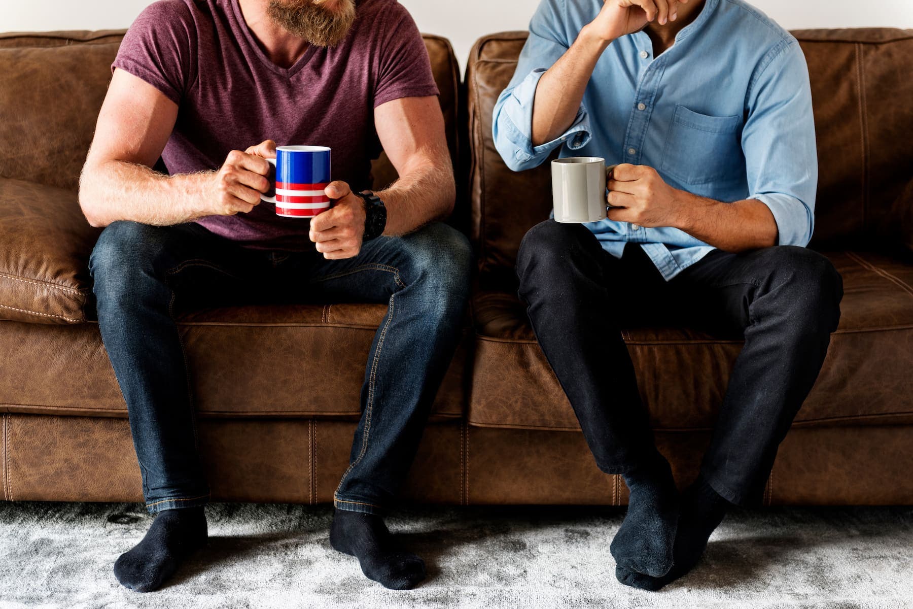 Two guys sitting on the sofa talking to each other