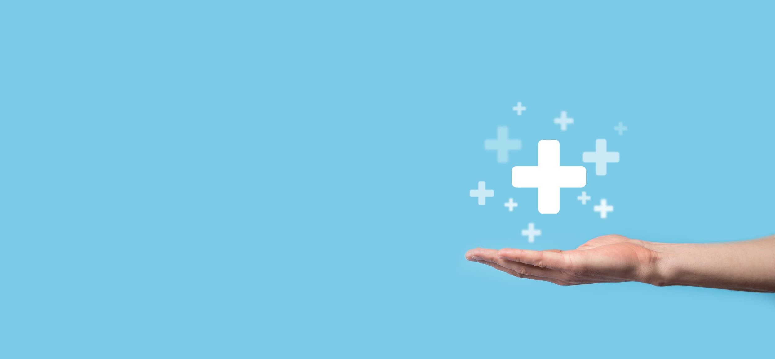 Male hand holding plus icon on blue background. Plus sign virtual means to offer benefits like healthcare and coverage for fertility treatments