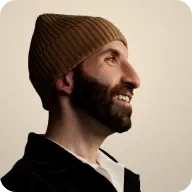 media_container_fixed_aspect_ratio_1713541552 Smiling man with beard wearing a knit hat looking right