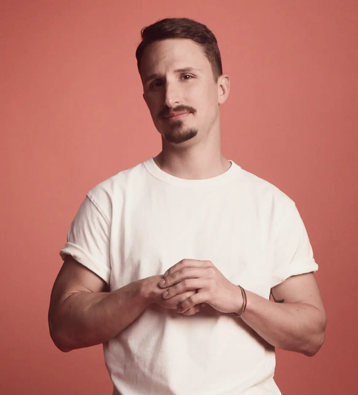 A man with joint hands, looking confidently at camera