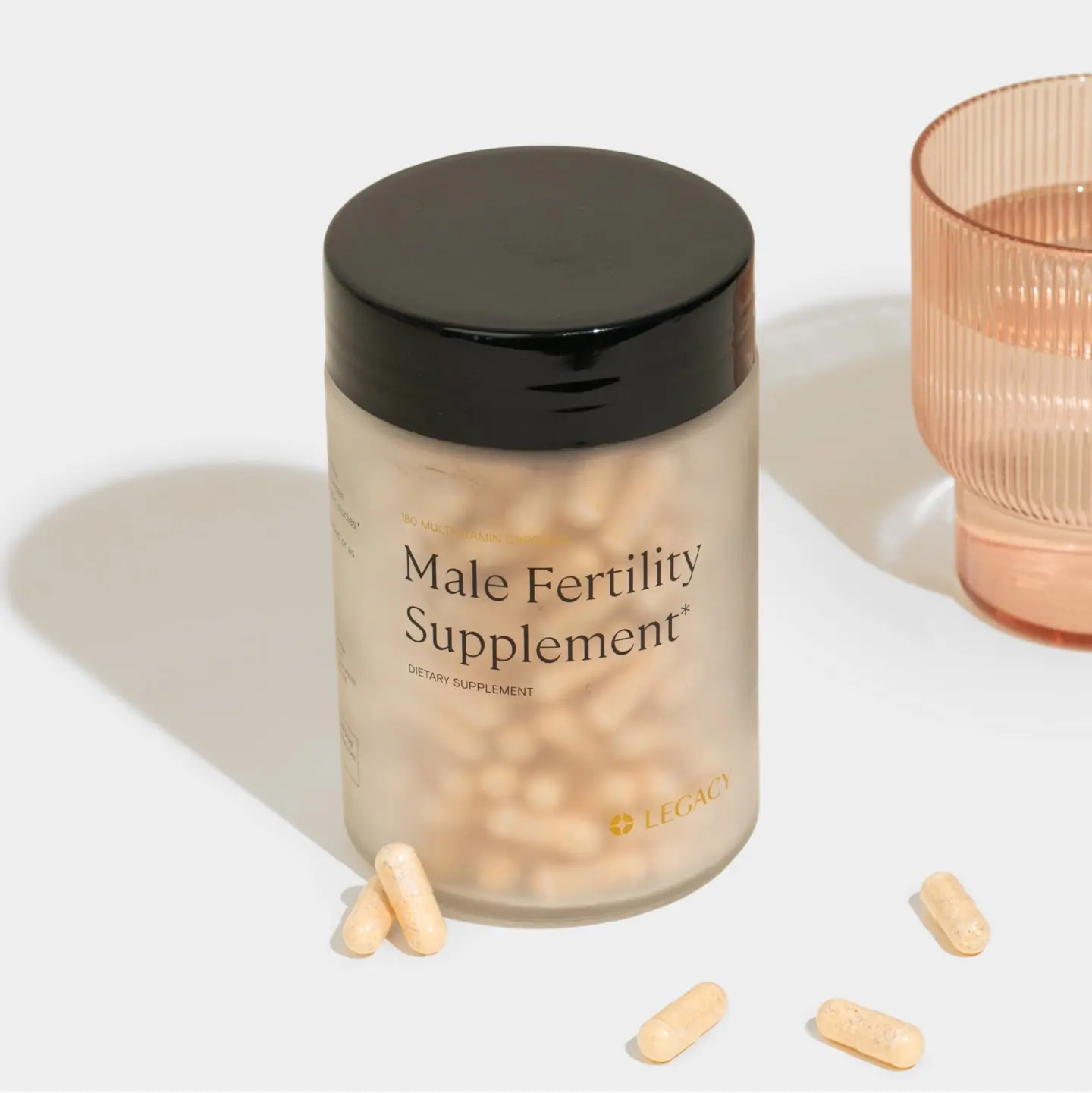 Male fertility supplement pill bottle with pills and water glass Male fertility supplement pill bottle with pills and water glass